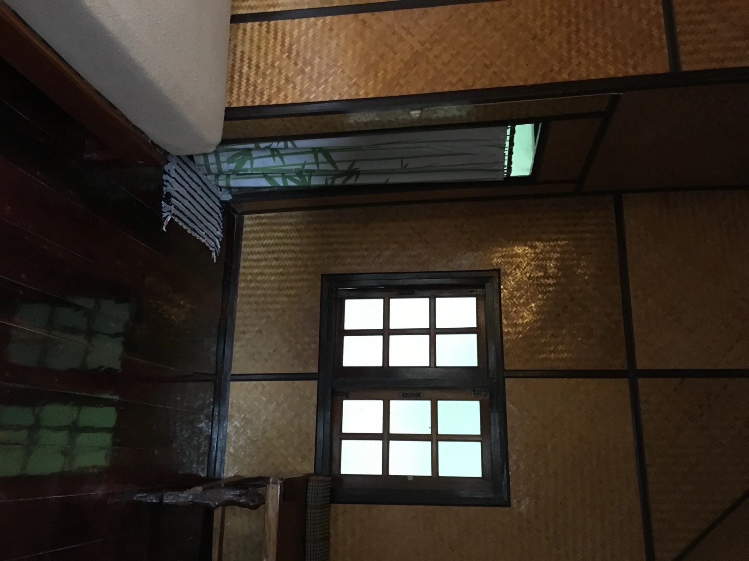 Inside a simple bungalow at Krit Raft House, woven bamboo walls and a window over the river.